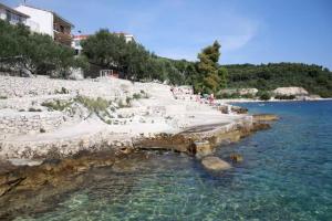 a beach with a group of people and the water at Apartmani Stine in Okrug Donji