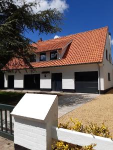 ein weißes Haus mit rotem Dach in der Unterkunft Villa De Strandjutter in Nieuwpoort