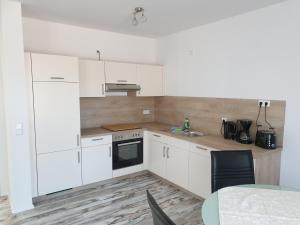 a kitchen with white cabinets and a sink and a table at Ferienwohnung Schmidt mit Terrasse in Neustrelitz +22 photos