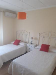 Cette chambre blanche comprend 2 lits avec des oreillers rouges. dans l'établissement Casa en Alcalá del Jucar, à Casas del Cerro