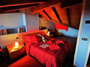 una camera con un letto rosso e un gatto steso sopra di Alba sul lago B&B a Stresa