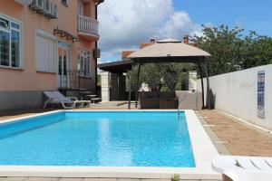 a swimming pool with an umbrella next to a house at Apartments Kimm in Poreč