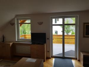 sala de estar con puerta corredera de cristal y TV en Apartment Brumec, en Bohinj