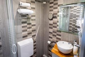 a bathroom with a sink and a toilet and a mirror at The Originals Boutique, Hôtel Neptune, Berck-sur-Mer in Berck-sur-Mer