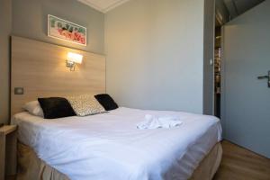 a bedroom with a white bed with towels on it at The Originals Boutique, Hôtel Neptune, Berck-sur-Mer in Berck-sur-Mer