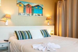 a bedroom with a white bed with a painting on the wall at The Originals Boutique, Hôtel Neptune, Berck-sur-Mer in Berck-sur-Mer