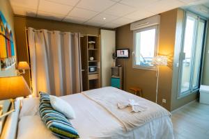 a bedroom with a bed with a bow on it at The Originals Boutique, Hôtel Neptune, Berck-sur-Mer in Berck-sur-Mer