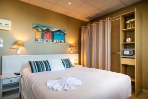 a bedroom with a bed with a bow on it at The Originals Boutique, Hôtel Neptune, Berck-sur-Mer in Berck-sur-Mer