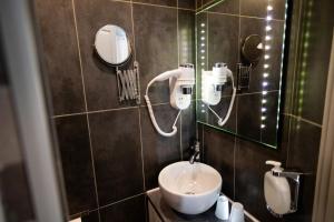 a bathroom with a sink and a mirror at The Originals Boutique, Hôtel Neptune, Berck-sur-Mer in Berck-sur-Mer