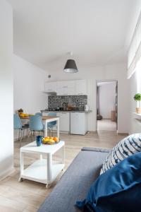 a white living room with a table and a kitchen at Apartamenty Dune in Jastarnia