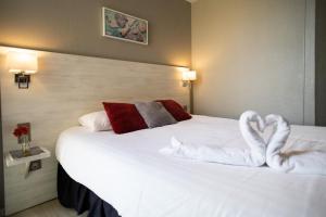 a hotel room with a white bed with towels on it at The Originals Boutique, Hôtel Neptune, Berck-sur-Mer in Berck-sur-Mer