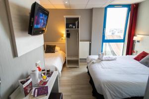 a hotel room with two beds and a flat screen tv at The Originals Boutique, Hôtel Neptune, Berck-sur-Mer in Berck-sur-Mer