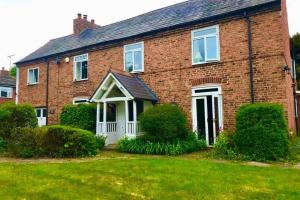 una casa de ladrillo rojo con una puerta blanca en Bretton House Farm Retreat en Chester
