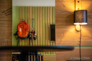un sac à dos orange suspendu sur un mur à côté d'une lampe dans l'établissement Hotel Les Restanques De Moustiers, à Moustiers-Sainte-Marie
