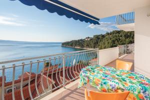 een balkon met een tafel en stoelen en de oceaan bij Beach Penthouse Diamond in Omiš