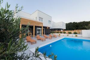 a villa with a swimming pool and patio furniture at Villa Belveder in Pag