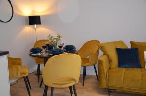 a dining room with a table and yellow chairs at Długie Ogrody Apartment 140 Gdańsk in Gdańsk