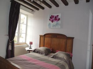 a bedroom with a bed with a wooden headboard and a window at La Ferme du Bourg in Éraines
