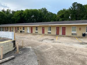 un bâtiment avec des portes rouges dans un parking dans l'établissement Budget Inn, à Dothan