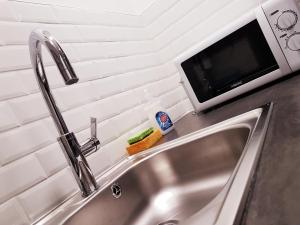 eine Küchenspüle mit einer Mikrowelle darüber in der Unterkunft SW Cosy Studio - Chambly Persan Roissy CDG in Persan