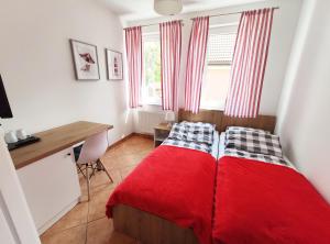sypialnia z czerwonym łóżkiem, biurkiem i oknem w obiekcie Willa Nord w mieście Pustkowo