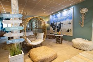a room with a wicker chair and a painting on the wall at The Originals Boutique, Hôtel Neptune, Berck-sur-Mer in Berck-sur-Mer