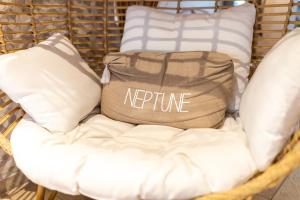 a rattan chair with a pillow and a bag at The Originals Boutique, Hôtel Neptune, Berck-sur-Mer in Berck-sur-Mer