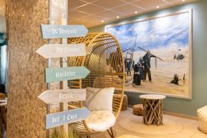 a room with a wicker chair and signs on the wall at The Originals Boutique, Hôtel Neptune, Berck-sur-Mer in Berck-sur-Mer