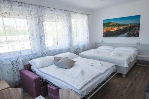 2 camas en una habitación con paredes y ventanas blancas en Apartmány Pemag Mikulov en Mikulov