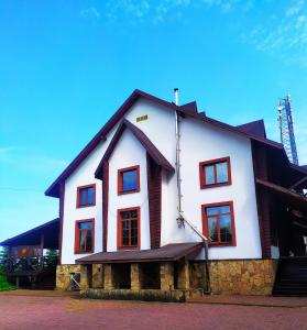 Una gran casa blanca con ventanas rojas. en Pan Otaman, en Pisarevka