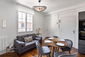 uma sala de estar com um sofá, uma mesa e cadeiras em Carré Sainte-Anne - Appt en plein centre historique em Rennes