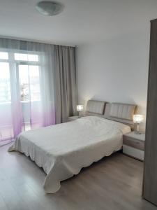 een witte slaapkamer met een groot bed en een raam bij Garsoniera Soarelui in Eforie Nord