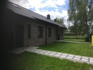 a brick house with a grass yard in front of it at Apartments by the beach in Trzebież