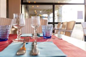 a table with glasses and utensils on a table at The Originals Boutique, Hôtel Neptune, Berck-sur-Mer in Berck-sur-Mer