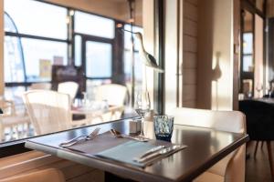 a table in a restaurant with a glass of wine at The Originals Boutique, Hôtel Neptune, Berck-sur-Mer in Berck-sur-Mer