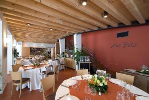 a restaurant with white tables and chairs and a red wall at Borgo Ronchetto in Salgareda