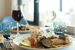 un plato de comida en una mesa con una copa de vino en The Originals Boutique, Hôtel Neptune, Berck-sur-Mer (Inter-Hotel), en Berck-sur-Mer