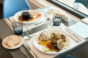 two plates of food on a table with glasses of wine at The Originals Boutique, Hôtel Neptune, Berck-sur-Mer in Berck-sur-Mer