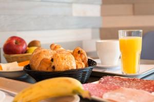 uma bandeja com uma cesta de pão e um copo de sumo de laranja em The Originals Boutique, Hôtel Neptune, Berck-sur-Mer (Inter-Hotel) em Berck-sur-Mer