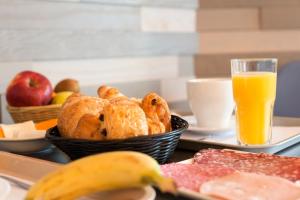 a tray with a basket of bread and a glass of orange juice at The Originals Boutique, Hôtel Neptune, Berck-sur-Mer in Berck-sur-Mer