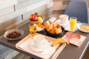 einen Tisch mit einem Tablett mit Frühstückszutaten und Getränken in der Unterkunft The Originals Boutique, Hôtel Neptune, Berck-sur-Mer (Inter-Hotel) in Berck-sur-Mer
