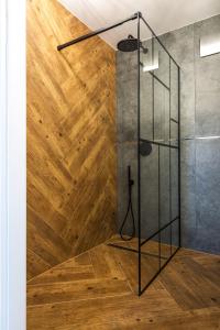 a shower in a bathroom with a wooden floor at Apartament u Rudej in Tolkmicko