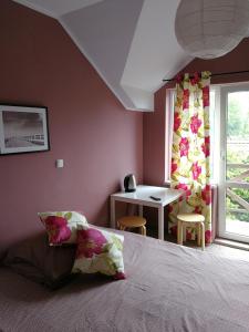 a bedroom with a bed and a desk and a window at Cicha Dolinka in Stegna