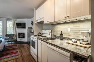 a kitchen with white cabinets and a sink at Tremblant Studio Kona by My Tremblant Location in Mont-Tremblant