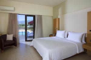 una camera con un grande letto bianco e una sedia di Elite City Resort a Kalamáta
