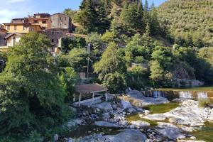 a bench sitting next to a river with houses at CASA BACICCIA in Badalucco