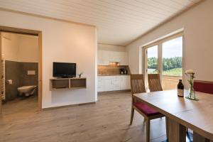 eine Küche und ein Esszimmer mit einem Tisch und einem TV in der Unterkunft Steinkellerhof in Völlan