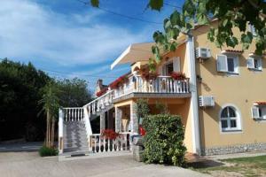 een groot geel huis met een veranda en een balkon bij Apartments Nella in Sveti Anton