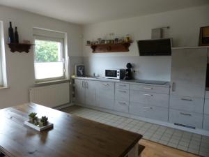 a kitchen with white cabinets and a wooden table at Die Gefährten in Oberhausen