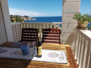 a table with a bottle of wine and glasses on a balcony at Apartments Tanja in Zavalatica